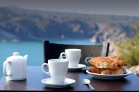 Teapot, cups and plate of croissants on a table over sea view