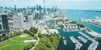 Aerial view of the Toronto skyline with the CN Tower, a waterfront marina full of boats and a green park